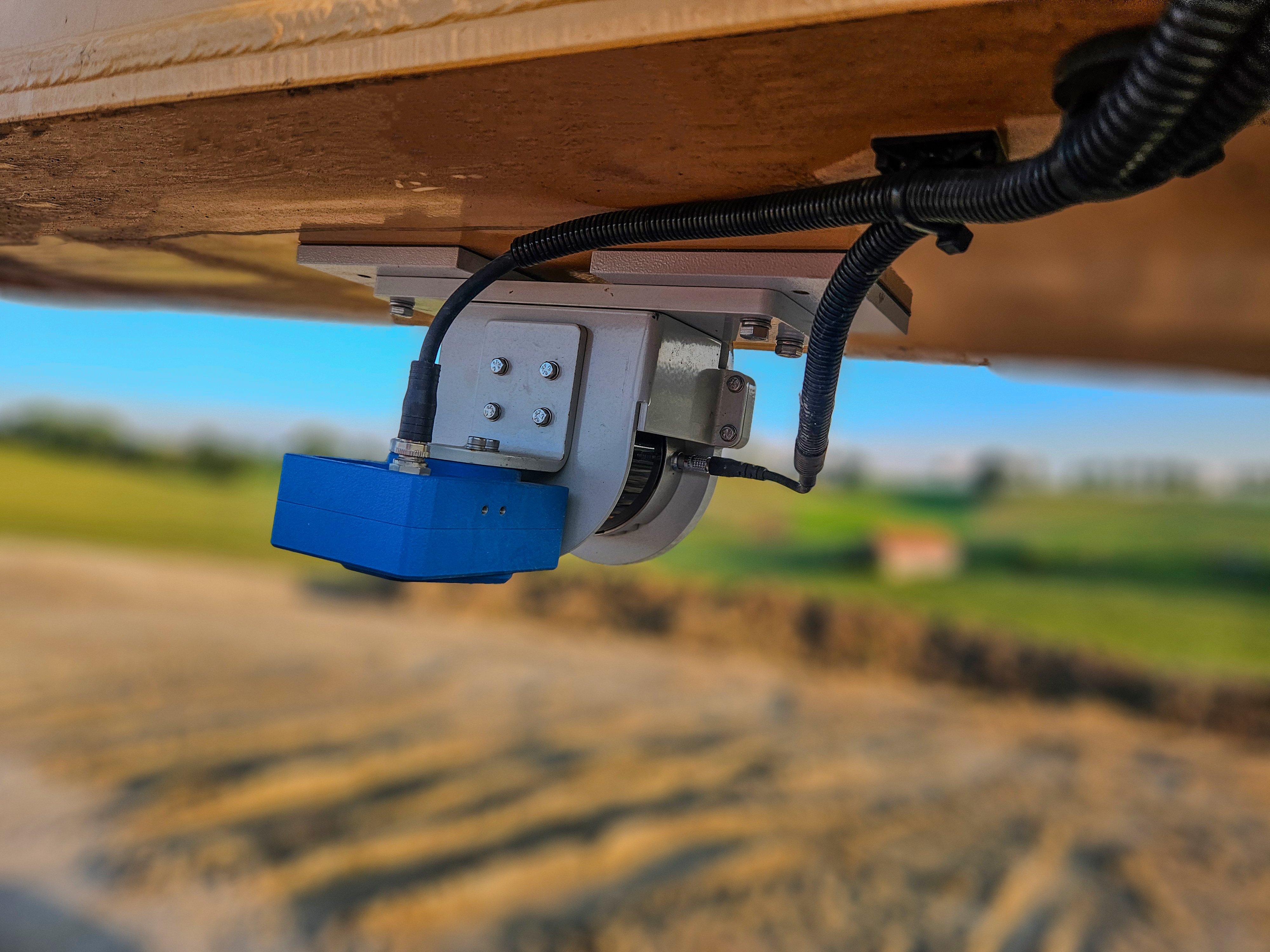 SDX-4DVision sensor in a blue housing on a metal bracket under a machine arm, with its cable routed along the bracket