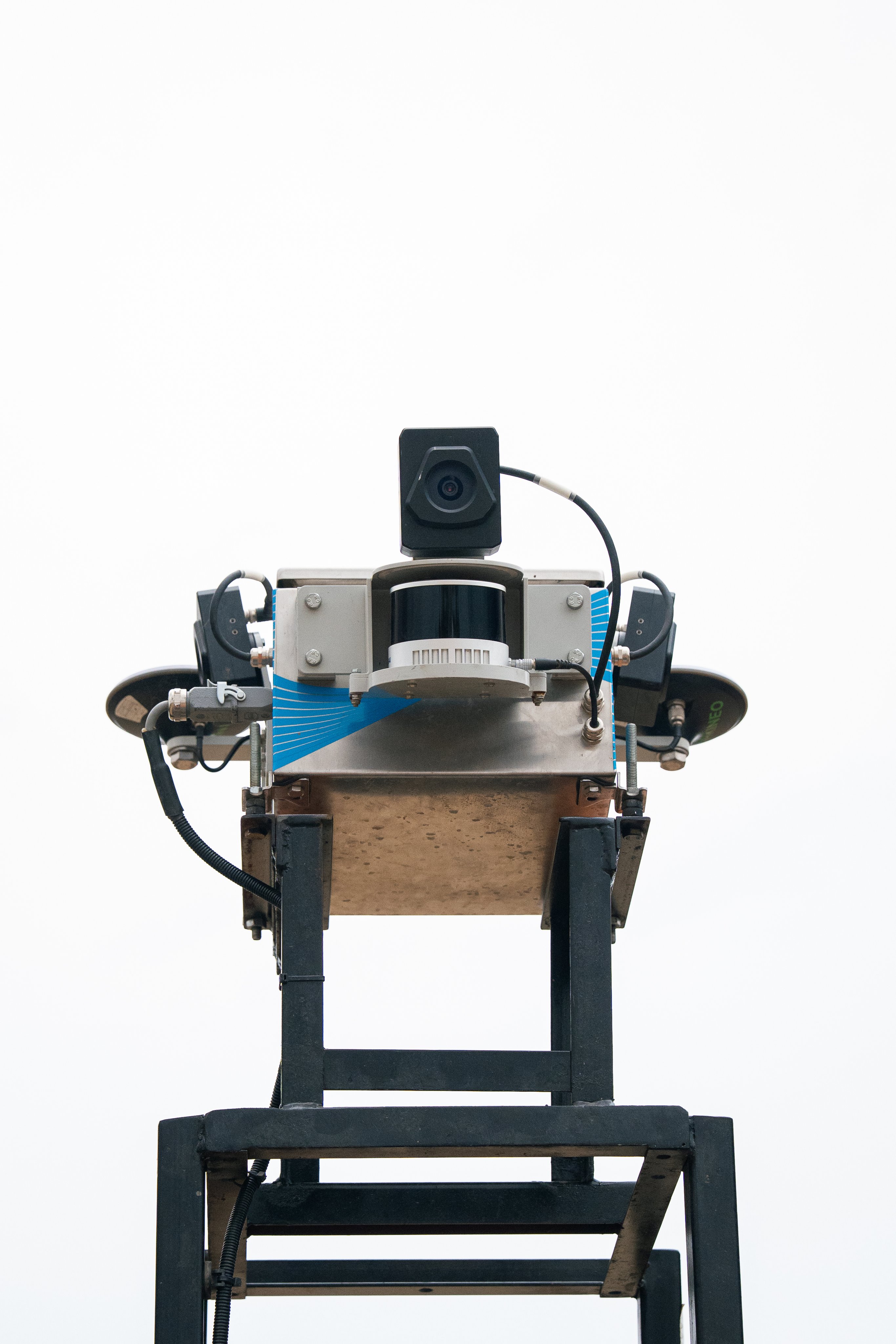 SDX-Compact sensor head with a camera, mounted on a metal mast against a white sky